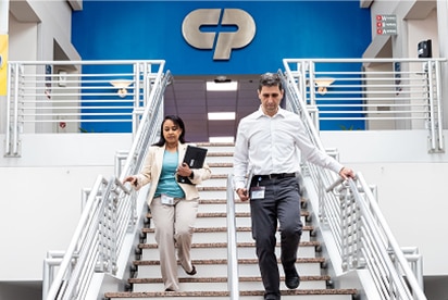 Colgate-Palmolive employees going down a flight of stairs with a Colgate-Palmolive logo behind them on a blue wall.