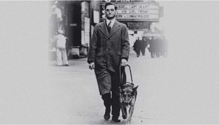 Black-and-white photo of Dr. Mark L. Morris walking alongside his guide dog Buddy on a city street in the 1930s.