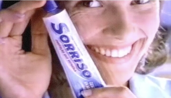 Woman smiling and holding a Sorriso toothpaste tube close to her face in an ad from the 1990s.
